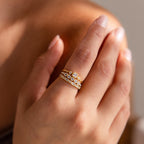 Hand wearing a stacked gold Art Deco diamond ring set with various cut stones, shown in soft natural lighting.