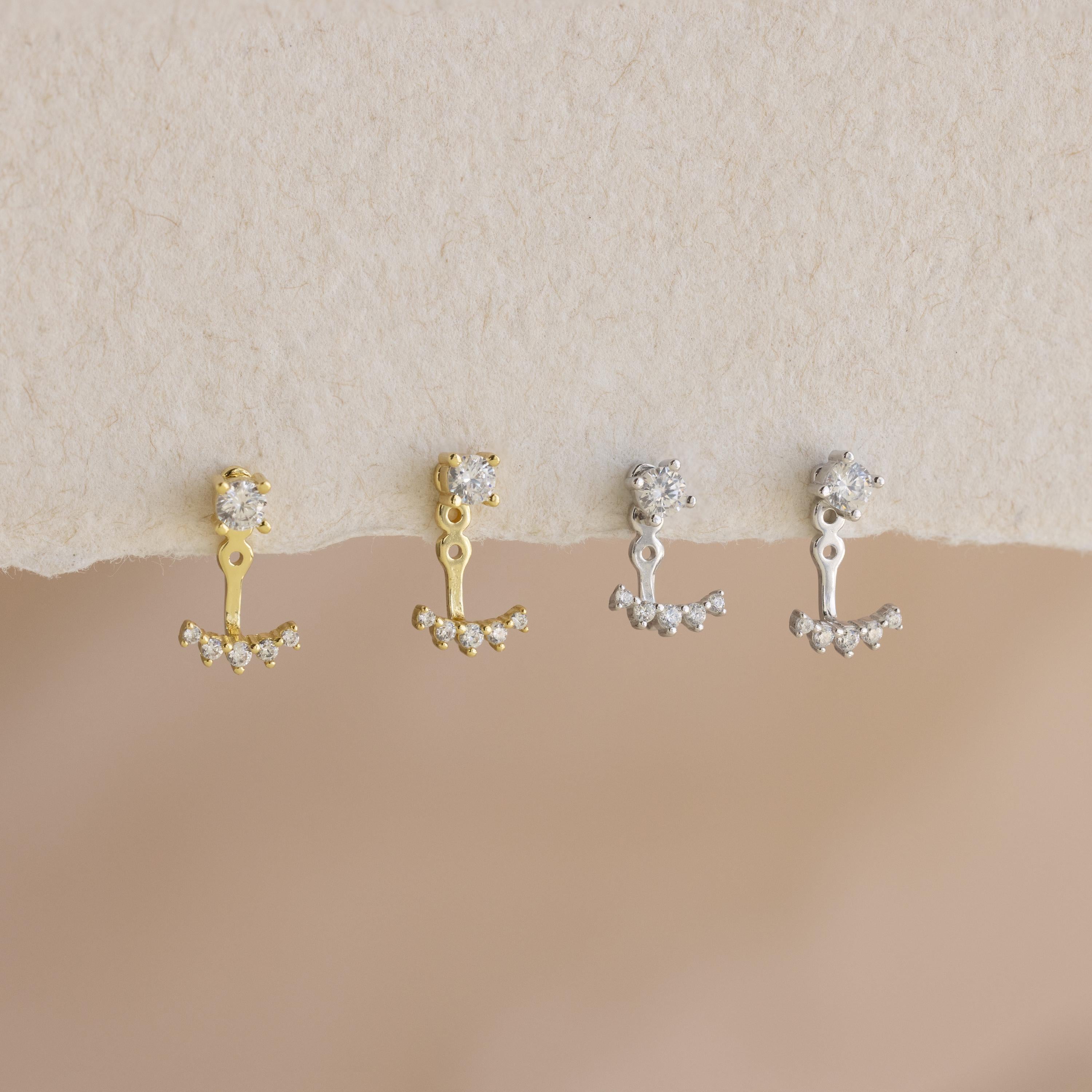 A pair of Round Diamond Ear Jackets displayed on a textured cream surface.