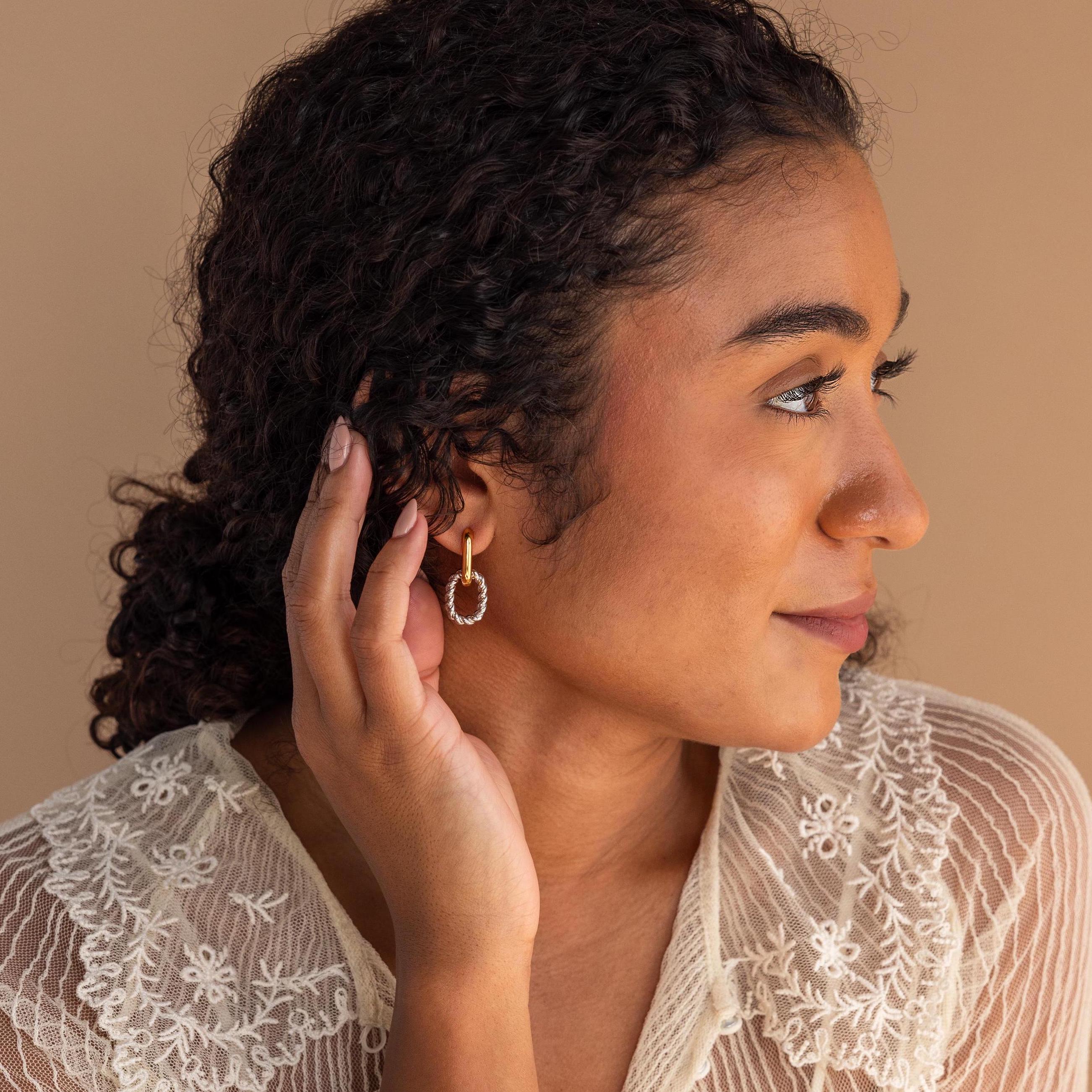 A woman with curly hair wears a white lace top and Mixed Metal Link Hoops.