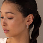 Woman with braided hair wearing Inside Out Heart Diamond Hoops, featuring multiple sparkling diamonds, looking down with a neutral expression.
