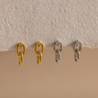 Two pairs of Link Drop Studs, one in gold and one in silver, elegantly displayed on a textured beige surface—perfect earrings for any occasion.