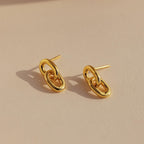 Link Drop Studs are shown on a beige surface with soft lighting, highlighting their elegant chain link design and casting delicate shadows.