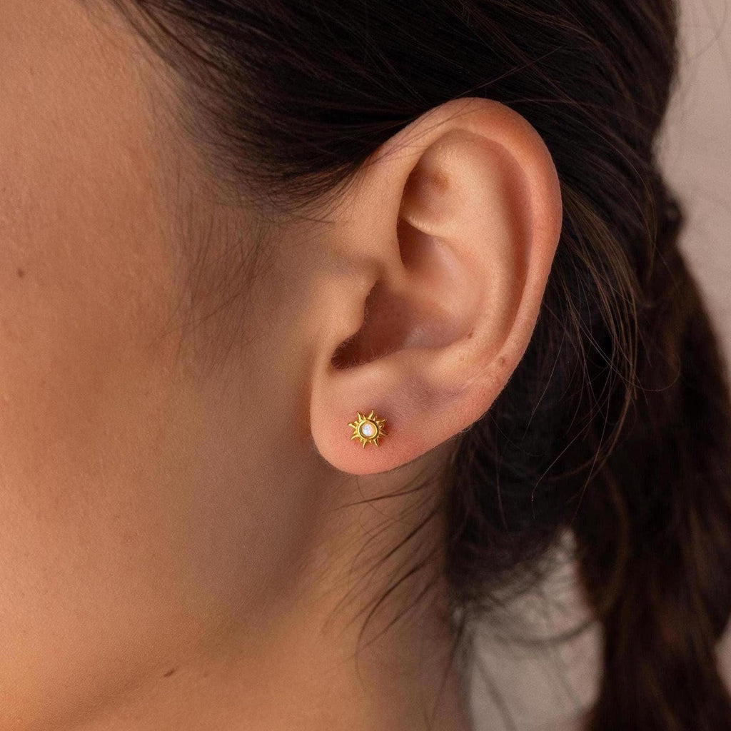 A close-up of a woman's ear adorned with delicate Opal Sun Flat Back Studs, highlighting her love for celestial jewelry.