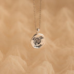 The Pet Portrait Coin Necklace is a silver custom piece featuring a round pendant engraved with a dog’s face and the name Cooper, perfect as pet memorial jewelry.