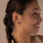 Woman with a braided hairstyle smiling, showing off her Link Drop Studs—elegant silver chain link earrings that add a touch of sophistication to her look.
