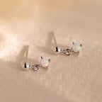 Dainty Opal Drop Studs: Small round opals set in silver, these lightweight earrings rest on a soft beige textured surface—perfect for adding everyday elegance.