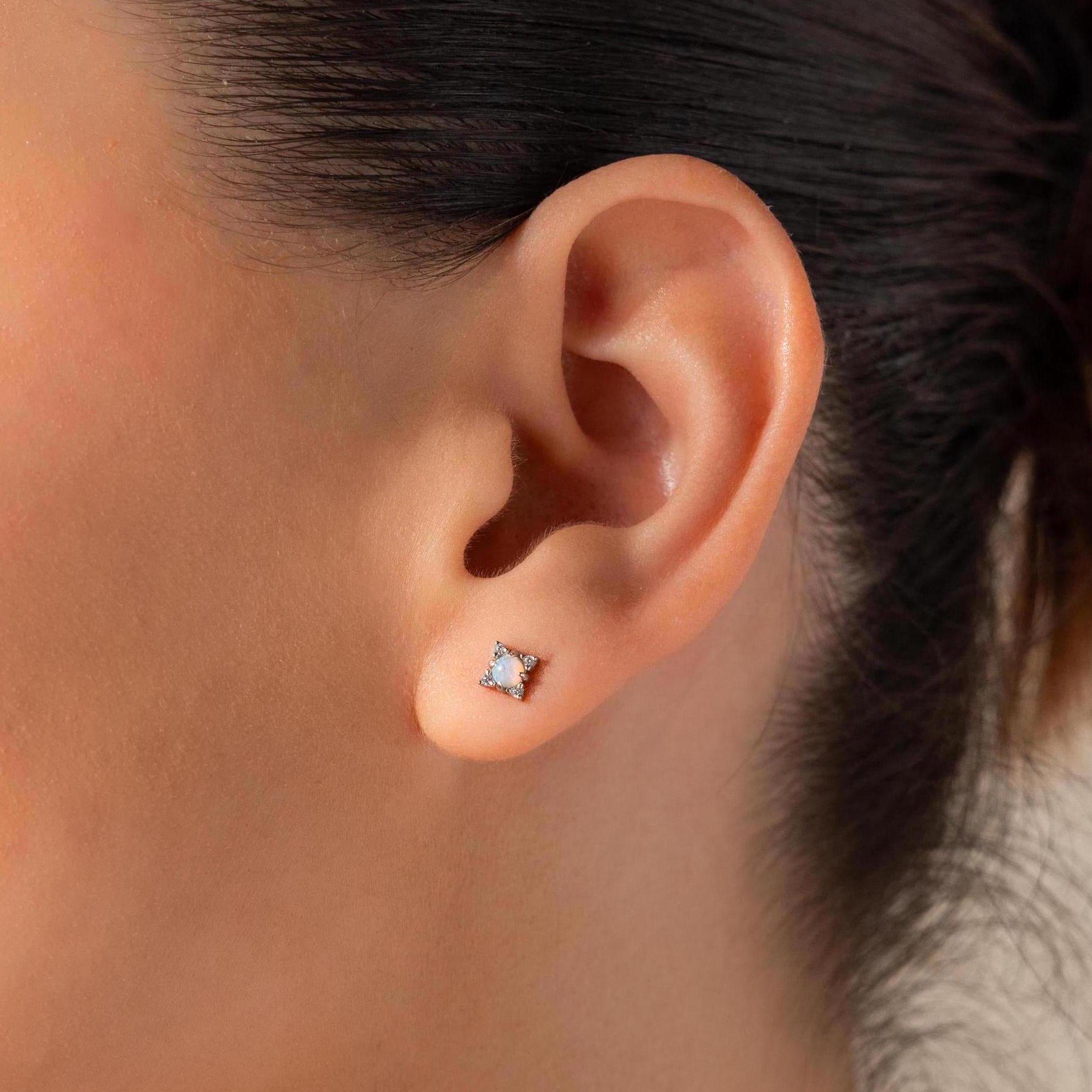Close-up of a woman's ear wearing Opal Diamond Star Studs—a small, square-shaped earring that evokes celestial and star jewelry.