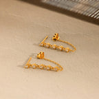Diamond Chain Drop Earrings with sparkling stones, beautifully displayed on a beige textured surface. A charming gift for her.