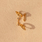 The Dainty Pave Earrings Set features sparkling pave accents and a chic design, displayed on a textured beige background—ideal for fans of elegant earrings.