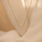 Diamond Sun Necklace with a radiant sunburst pendant set with sparkling diamonds, elegantly displayed against a soft beige fabric background.