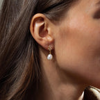 A close-up of a woman’s ear adorned with elegant Pearl Diamond Drop Earrings.