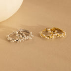 Two pairs of pearl earrings, featuring elegant Pearl Cluster Huggies in Sterling Silver, displayed on a beige surface—ideal as bridal earrings or for any special occasion.