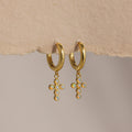 Opal Cross Huggies: gold huggie earrings with iridescent opal cross charms, shown on textured paper.