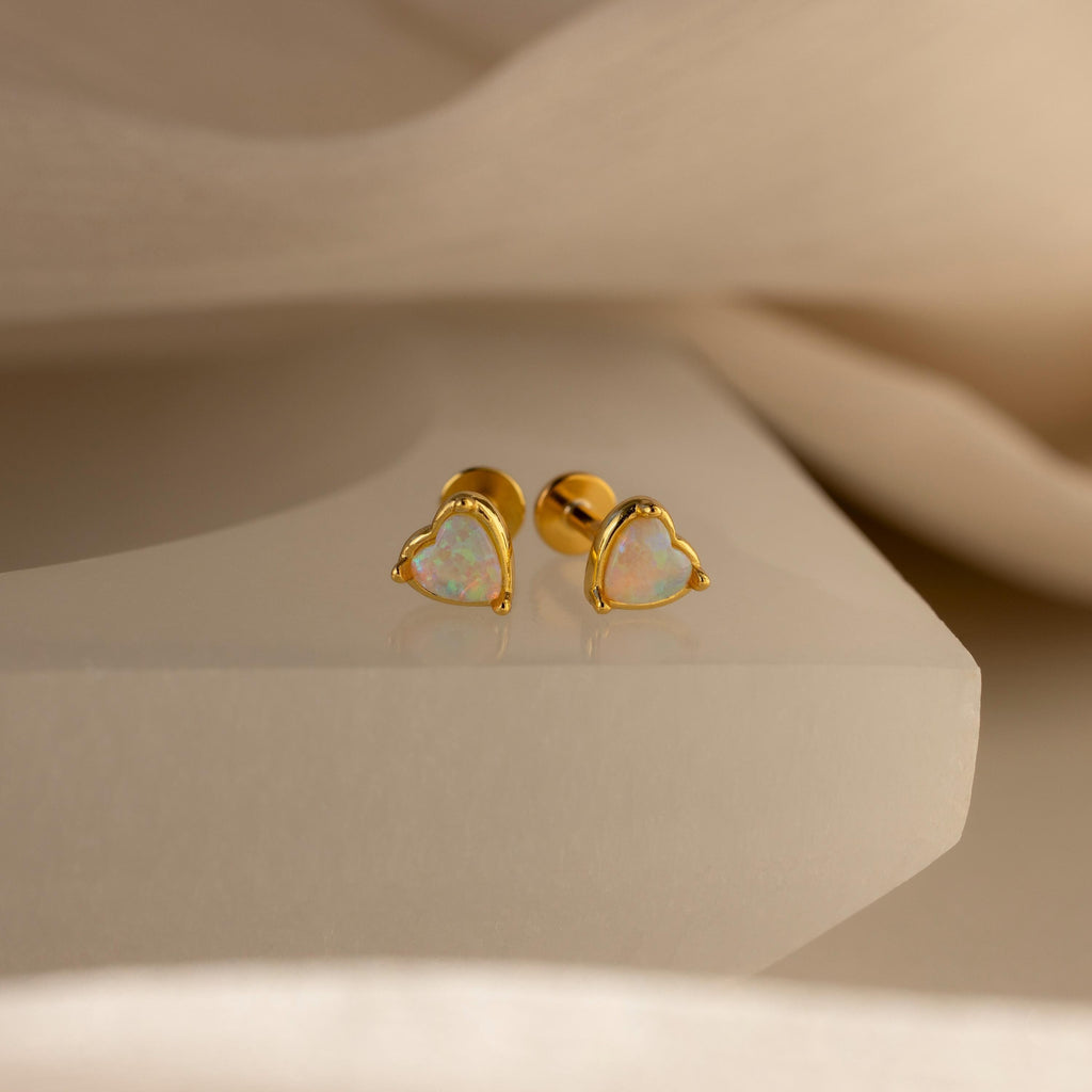 Opal Heart Flat Back Studs featuring heart-shaped opal stones, ideal as gemstone or birthstone jewelry, beautifully displayed on a smooth, cream-colored surface.