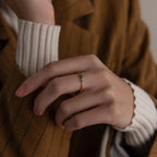 A hand wearing the Toi et Moi Princess Birthstone Ring with a blue stone, paired with a brown pinstripe blazer and white sweater.