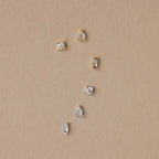 The Mixed Diamond Flat Back Stud Set features six small gold and silver flat back stud earrings with clear stones, arranged on a beige background.