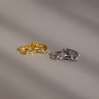 The Hammered Rectangle Hoops, featuring gold and silver textured geometric designs, are displayed side by side on a smooth, neutral surface.