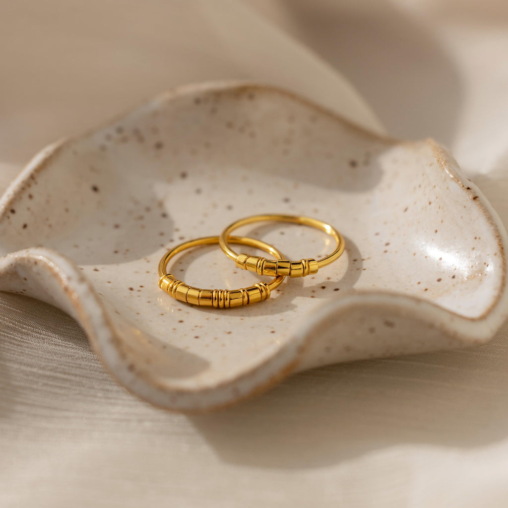 The Dainty Morse Code Ring with textured details rests on a wavy, speckled ceramic dish against a soft beige background.