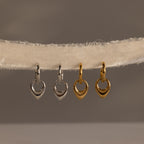 Two silver and two gold heart-shaped charms hang on a textured, off-white fabric string—perfect for pairing with your favorite Bold Teardrop Hoops for a charming, coordinated look.