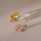 The Duo Initial Heart Ring features engraved decorative initials on a filigree band, available in gold, silver, and rose gold, displayed on a neutral background.