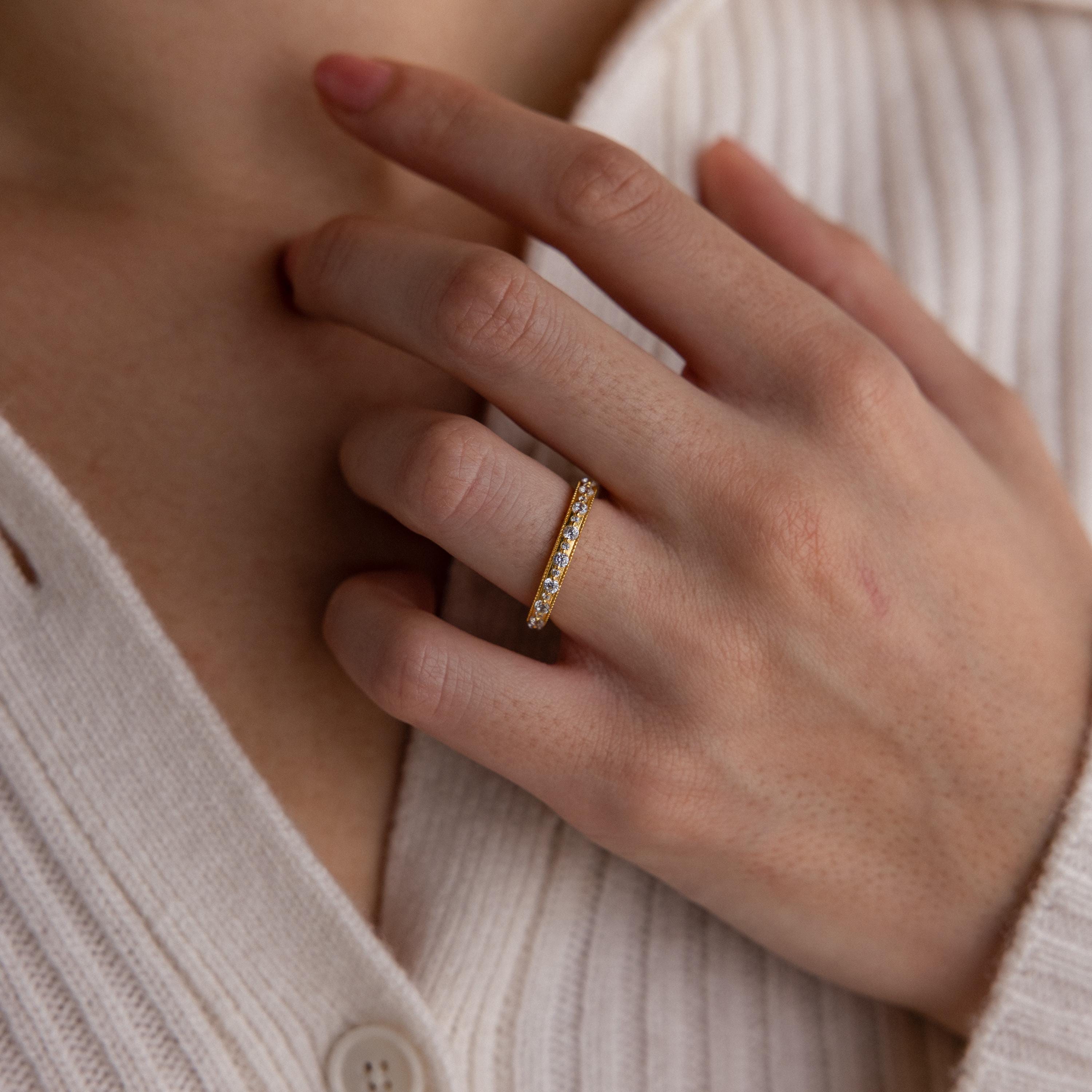 A hand wearing the Diamond Eternity Ring, featuring sparkling diamonds, rests on a cream-colored ribbed sweater.