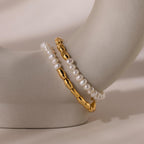 The Duo Beaded Pearl Bracelet, featuring white pearls and gold beaded accents, is displayed on a curved beige surface for an elegant, layered look.