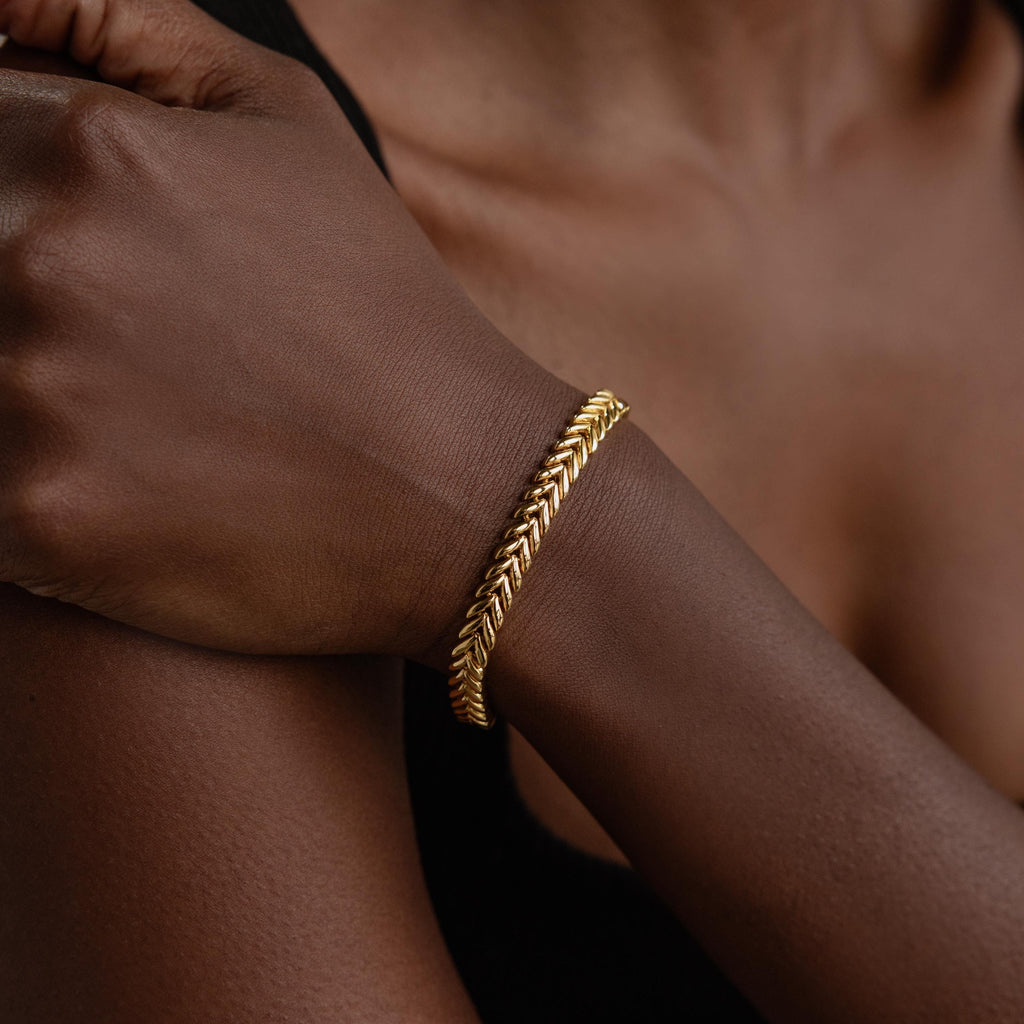 A V-Link Chain Tennis Bracelet graces a person's wrist, its sculptural links catching the light in a close-up of their hand and arm.