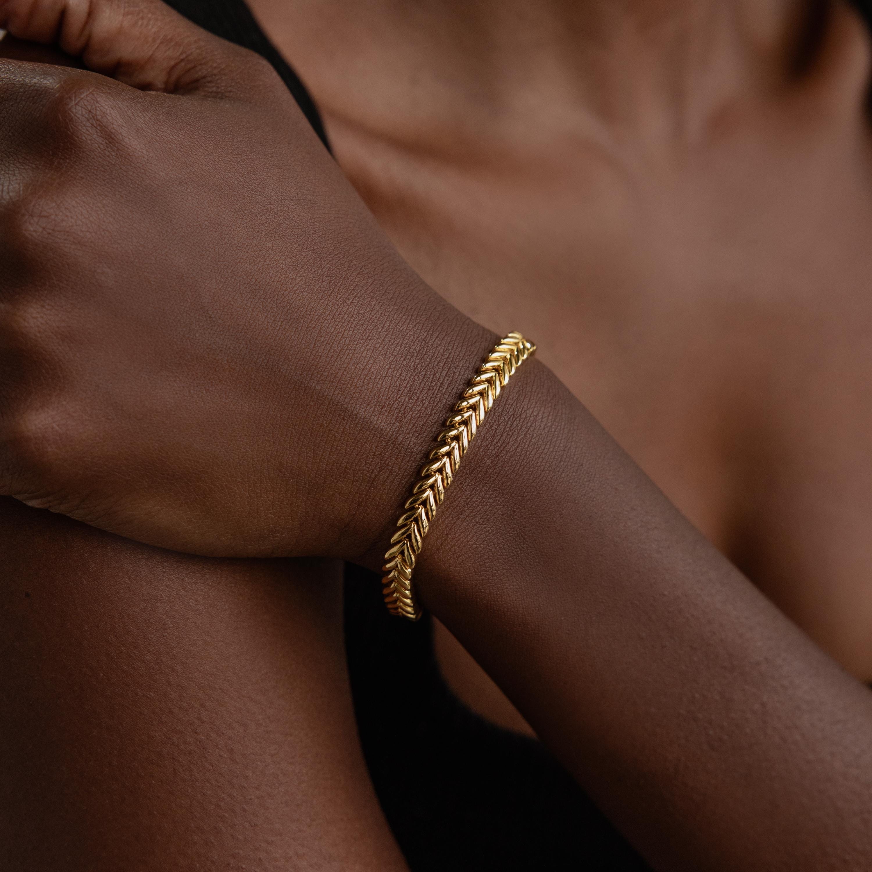 A V-Link Chain Tennis Bracelet graces a person's wrist, its sculptural links catching the light in a close-up of their hand and arm.