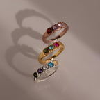 Three Vintage Multiple Birthstone Rings in rose gold, yellow gold, and silver shine with colorful stones on a neutral background.