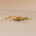 Three gold rings displayed flat with peridot and diamond designs, arranged side by side.