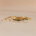 Three gold rings displayed flat with peridot and diamond designs, arranged side by side.