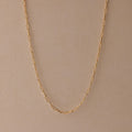 The Paperclip Chain Necklace is a delicate gold chain, ideal for layering and perfect for any style, shown on a beige background.