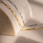 The Bold Paperclip Chain Necklace drapes elegantly over a curved marble surface in soft lighting, making a striking statement for a bold necklace look.