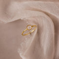 The Dainty Round Moonstone Ring features a subtle round gemstone, exuding understated elegance and grounding vibes when displayed on soft, textured fabric.