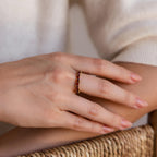 A hand wearing the Staggered Marquise Onyx Ring rests on a woven surface.