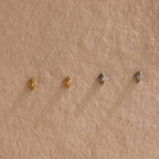 Two pairs of of gold and silver North Star Stud earrings hanging