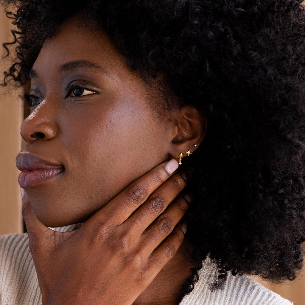 Model wearing gold North Star Stud Earrings with two other star celestial stud earrings