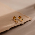 Close up of gold north star stud earrings with one screwed off, showcasing how the heart shaped flat back mechanism works