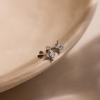 Flat lay of silver Pave North Star Earrings on soft beige surface