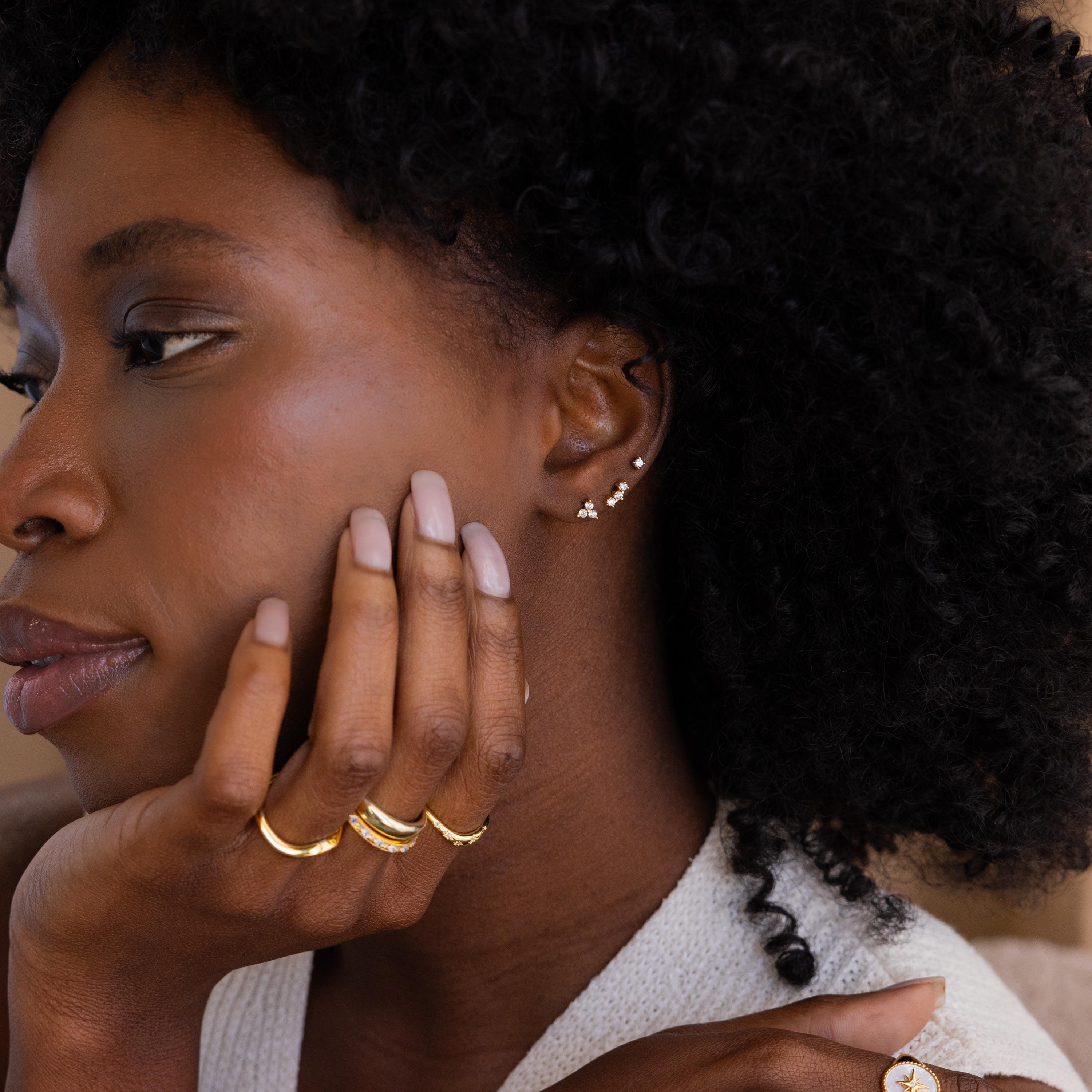 Model wearing a stacked set of 3 dainty CZ Diamond Constellation stud earrings with multiple gold stacking rings