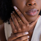 Celestial Wave Ring on model's middle finger. The gold ring features diamonds embedded within a star shaped design dotted sporadically on the face of the curved ring.