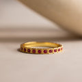 The Art Deco Ruby Eternity Ring features small square rubies set in a vintage milgrain gold bezel, displayed on a neutral surface.