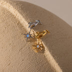 Two hand-and-star pendants—one in silver, one in gold—are styled side-by-side on a textured neutral surface.