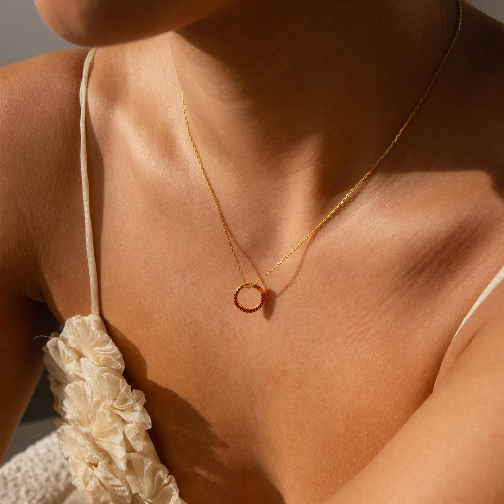 Woman wearing a Pave Garnet Charm Clip and a cream textured spaghetti strap top, sunlight on her skin—showcasing effortless style and jewelry personalization.