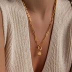 A single Opal Sun Charm is styled on a gold paperclip chain, worn on the chest with a textured knit top