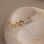 Flat lay of Gold & Silver Opal CZ Diamond Celestial Stud Earring Set with heart shaped flat backing unscrewed, displayed on round stone surface.