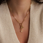 A close up of a rolo clasp charm necklace featuring the North Star Hand Charm and multiple other golden pendants