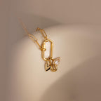 A detailed close-up of a necklace styled with three charms—including the Simple Heart Charm—hanging from a carabiner lock on a curved ceramic form.