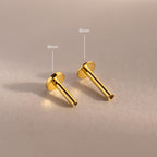 Close-up of two 18k gold Flat Back Posts lying down, showcasing the smooth finish and hollow post detail.