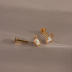 Gold opal and diamond flat back earrings laid out with visible backing mechanisms.